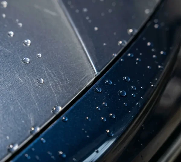Close-up detail of transparent paint protection film installed on vehicle front bumper showing pristine clear coat beneath